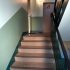Frisch gestrichene Wände in Grüntönen, Treppenhaus, Stufen und Wohnungstüren in Brauntönen