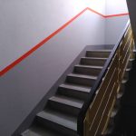 Treppenaufgang, Wand weiß und grau mit rotem Streifen.