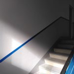 Treppenaufgang, Wand weiß und grau mit blauem Streifen.