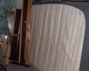 Eine alte Matratze mit Holzteilen eines Möbelstücks im Keller