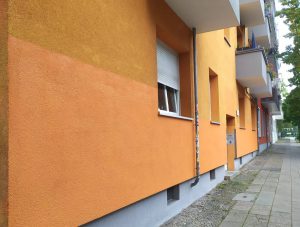 Orangefarbene Hausfassade, frische Farbe im Erdgeschoss setzt sich deutlich vom oberen Teil ab.