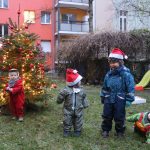 Kinder vor einem geschmückten Weihnachtsbaum im Hof.