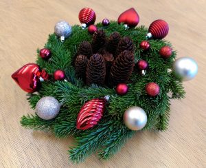 Weihnachtsgesteck mit Tanne, Zapfen und roten und silberfarbenen Kugeln